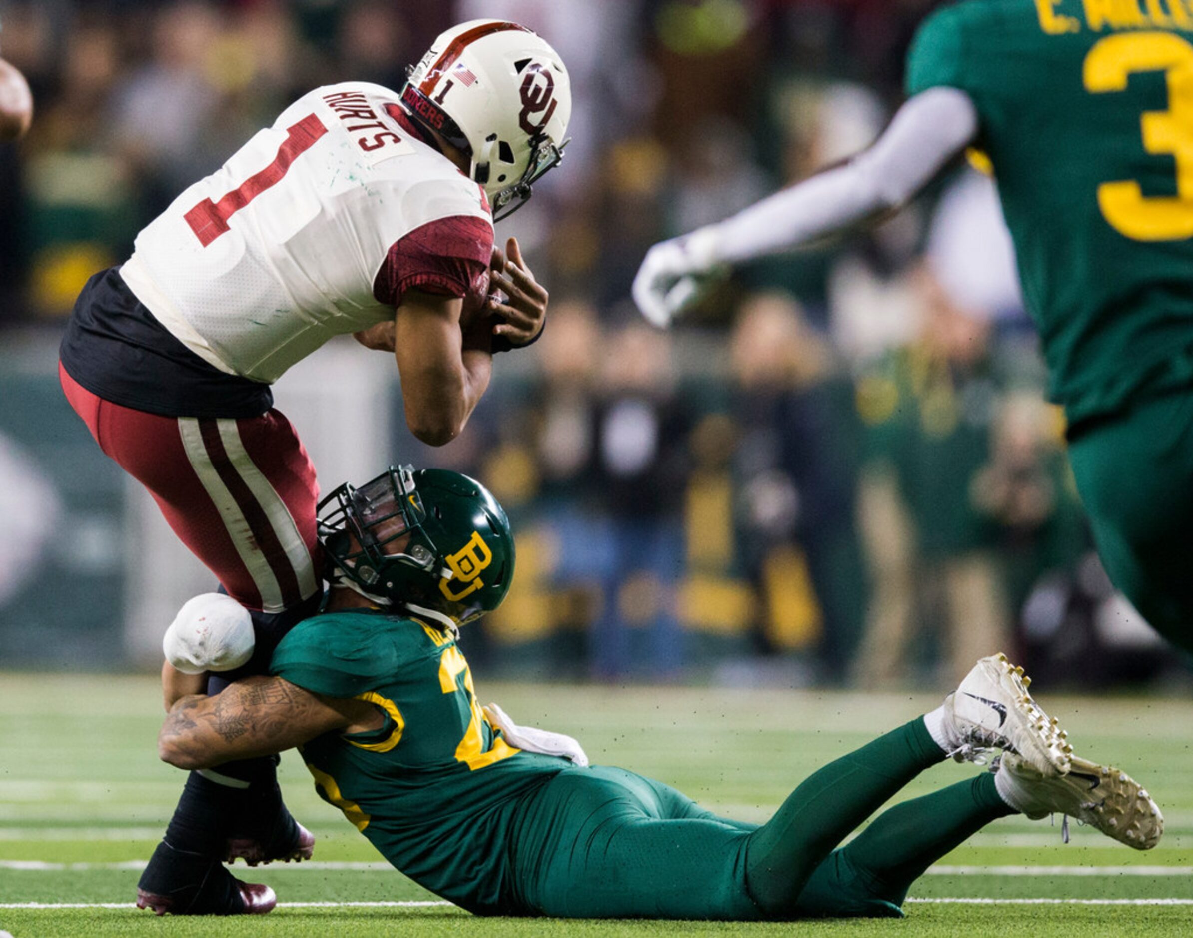 Oklahoma Sooners quarterback Jalen Hurts (1) is tackled by /b28d/ during the fourth quarter...