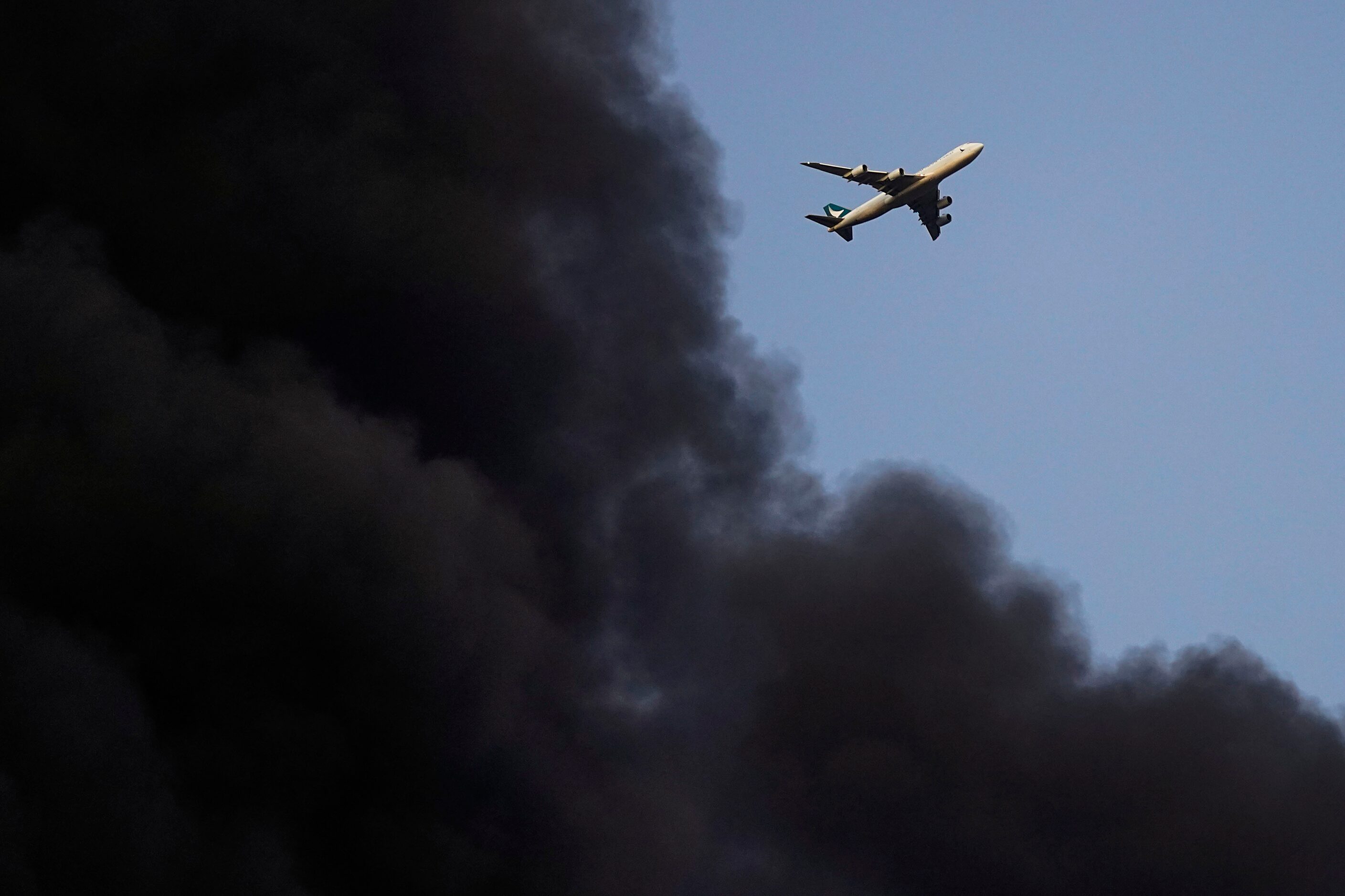 A plane on approach to DFW Airport passes over a plume of smoke from a massive blaze in an...