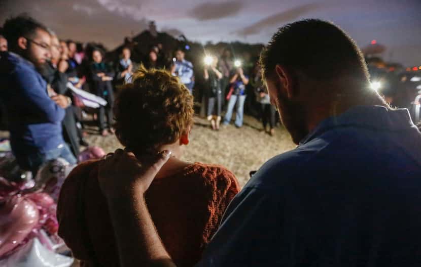 Nicole and Scott Snyder bow their heads in prayer at an Oct. 20 vigil for Sherin Mathews in...