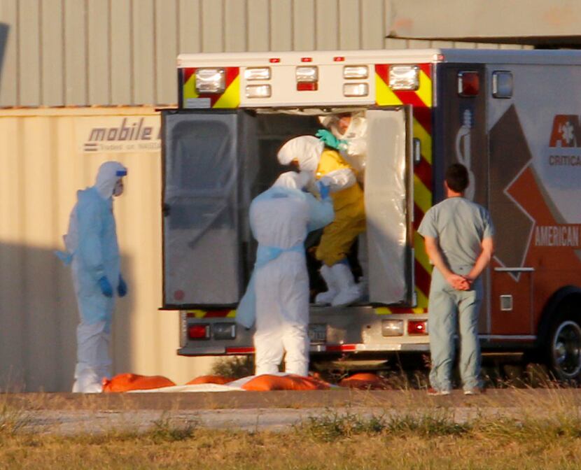 Ebola patient Nina Pham (in yellow) is helped off an ambulance at Dallas Love field for a...