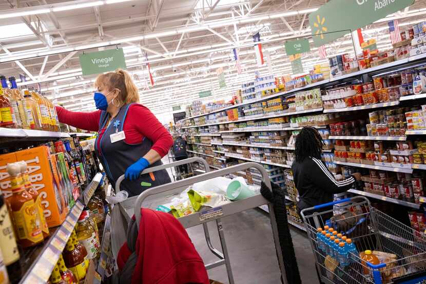 Shoppers shop as Maria Rios (left) stocks the shelf at the Walmart at 200 Short Blvd on...