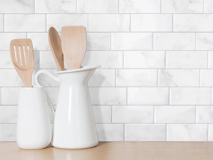 Kitchen counter with backsplash of white tiles and kitchen supplies on the counter