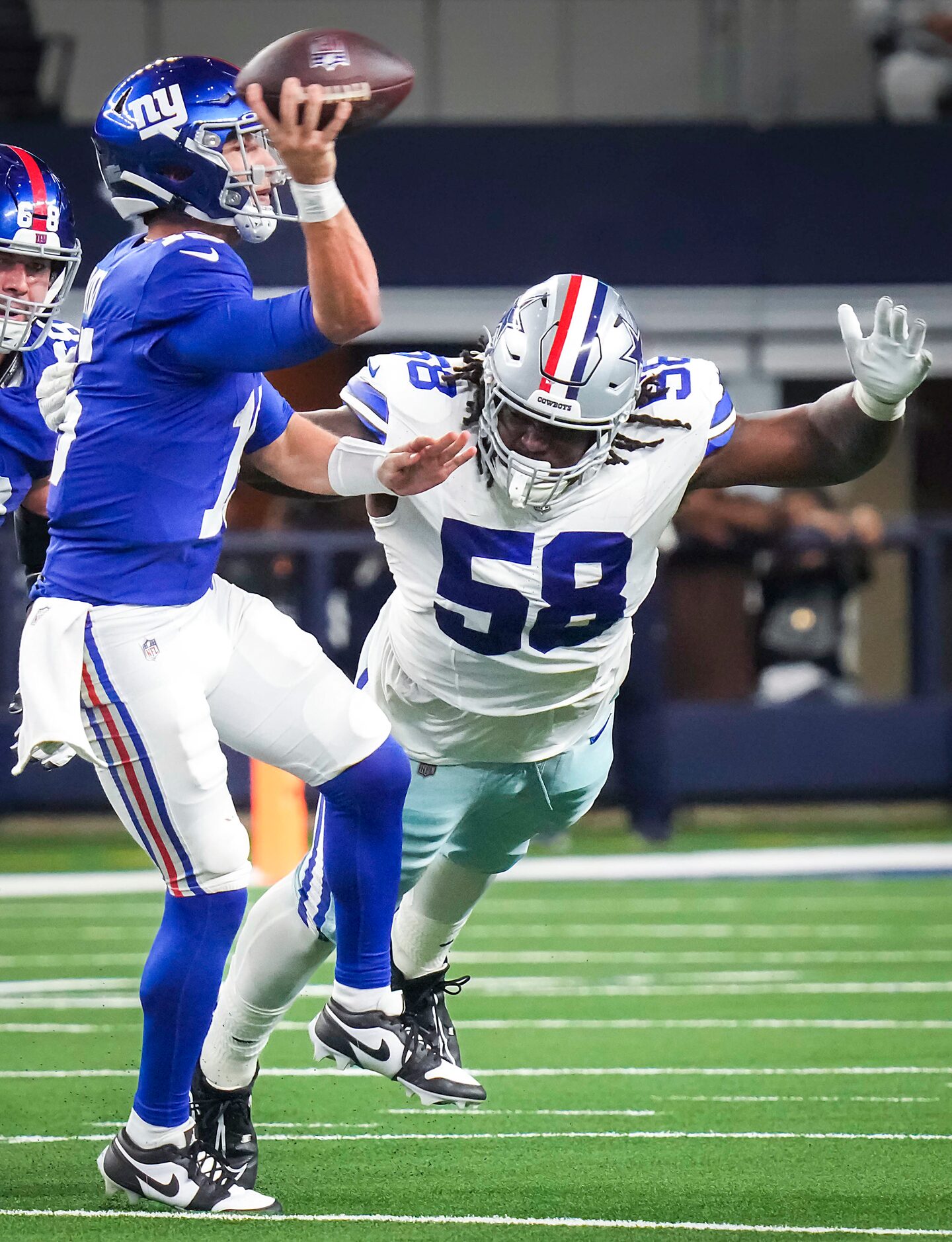 New York Giants quarterback Tommy DeVito (15) throws a pass under pressure from Dallas...