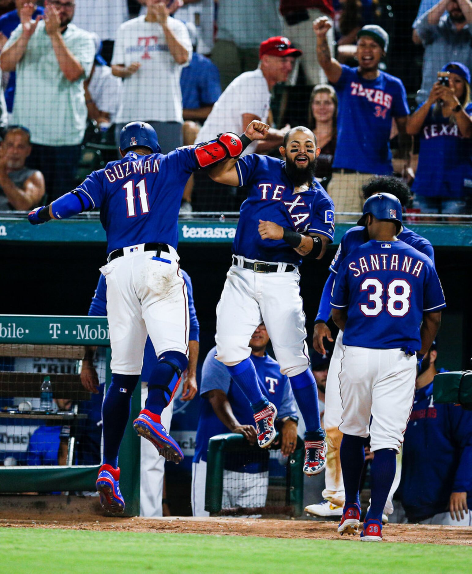 Texas Rangers' Ronald Guzman (11) is congratulated by Rougned Odor, center, after hitting a...