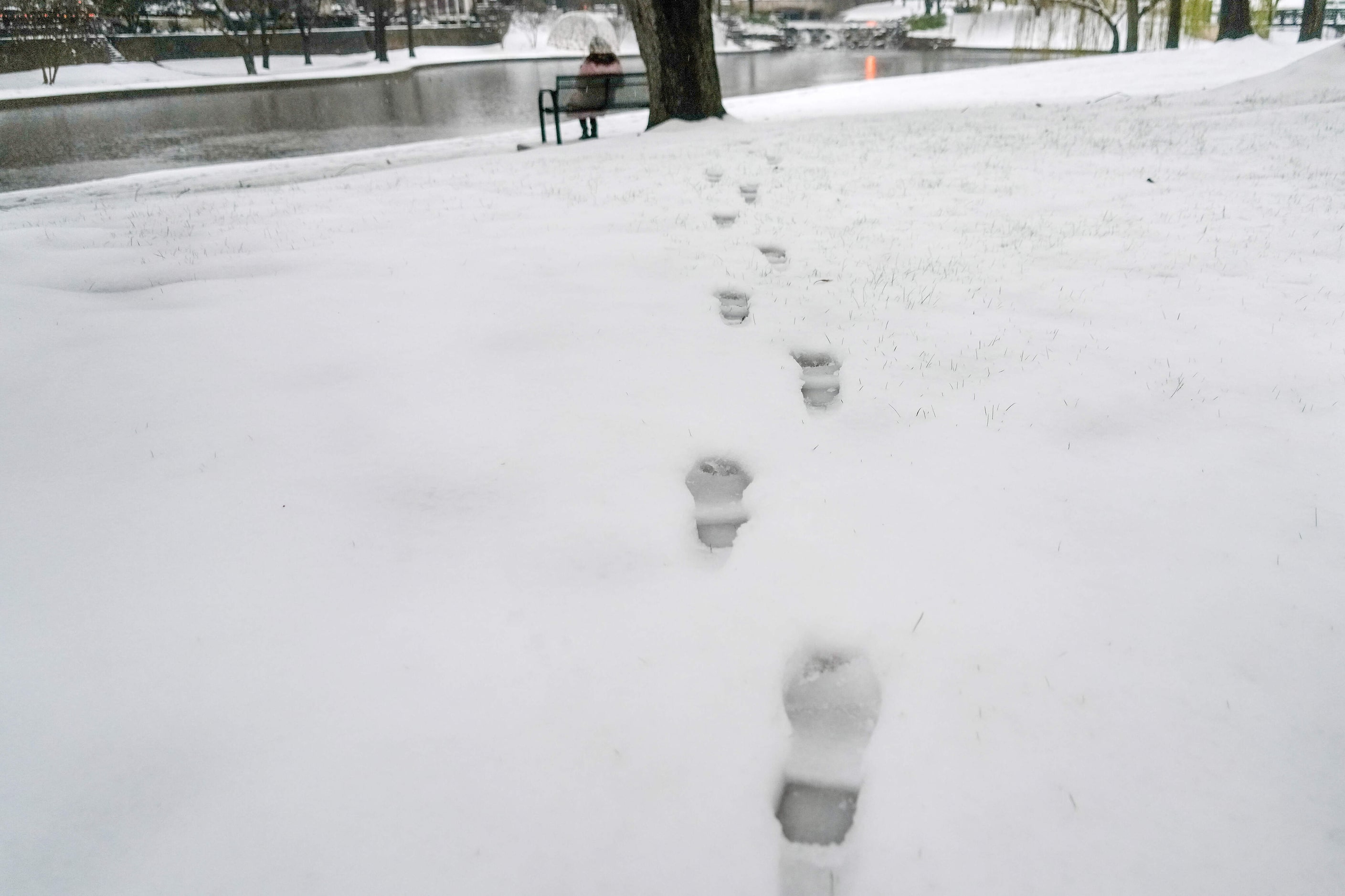 Footprints in the snow lead toward a bench in Lakeside Lake in the Lakeside Manor...