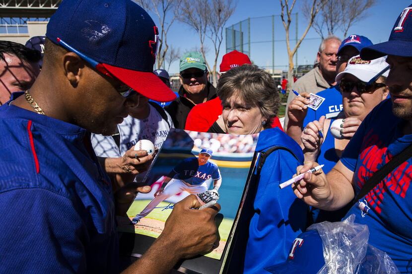 Texas Rangers third baseman Adrian Beltre signs autographs for fans during a spring training...