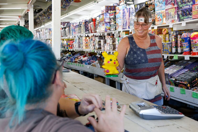 Employee Sandi Byrne shows a Pikachu fountain firework to Susie Ramirez and her son Aidan...