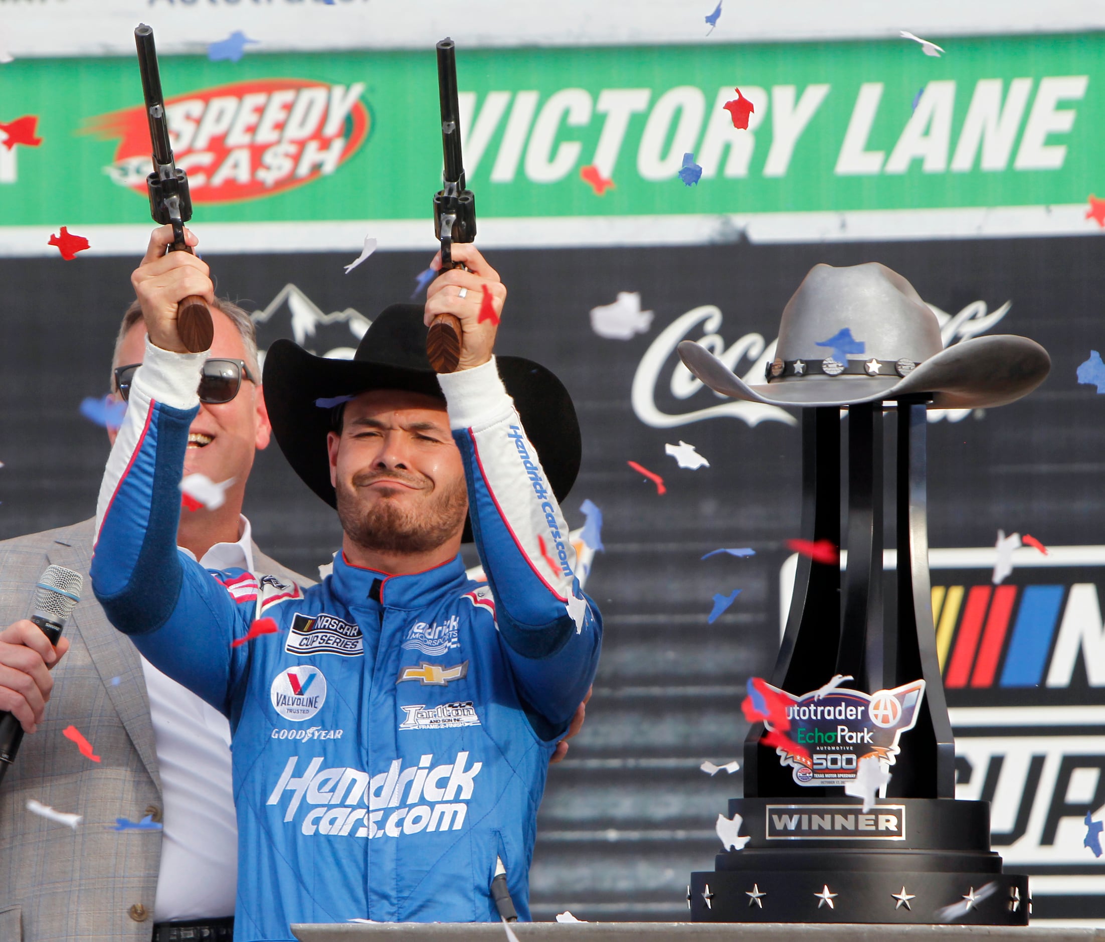 Kyle Larson grimaces as he fires a pair of pistols in celebration of his victory from behind...