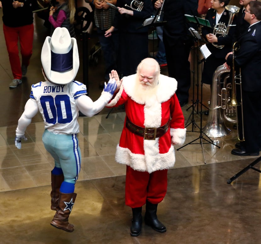 Dallas Cowboys mascot Rowdy gives a high-five to Santa Claus, played by Carl Anderson,...