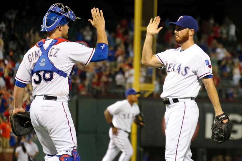 Texas Rangers catcher Chris Gimenez (38) and relief pitcher Sam Dyson (47) celebrate after...