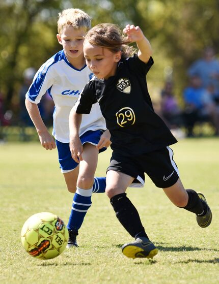 Harrison Rusaw, right, of PST Attack 2012, moves the ball forward passed a Texas Chaos 2011...