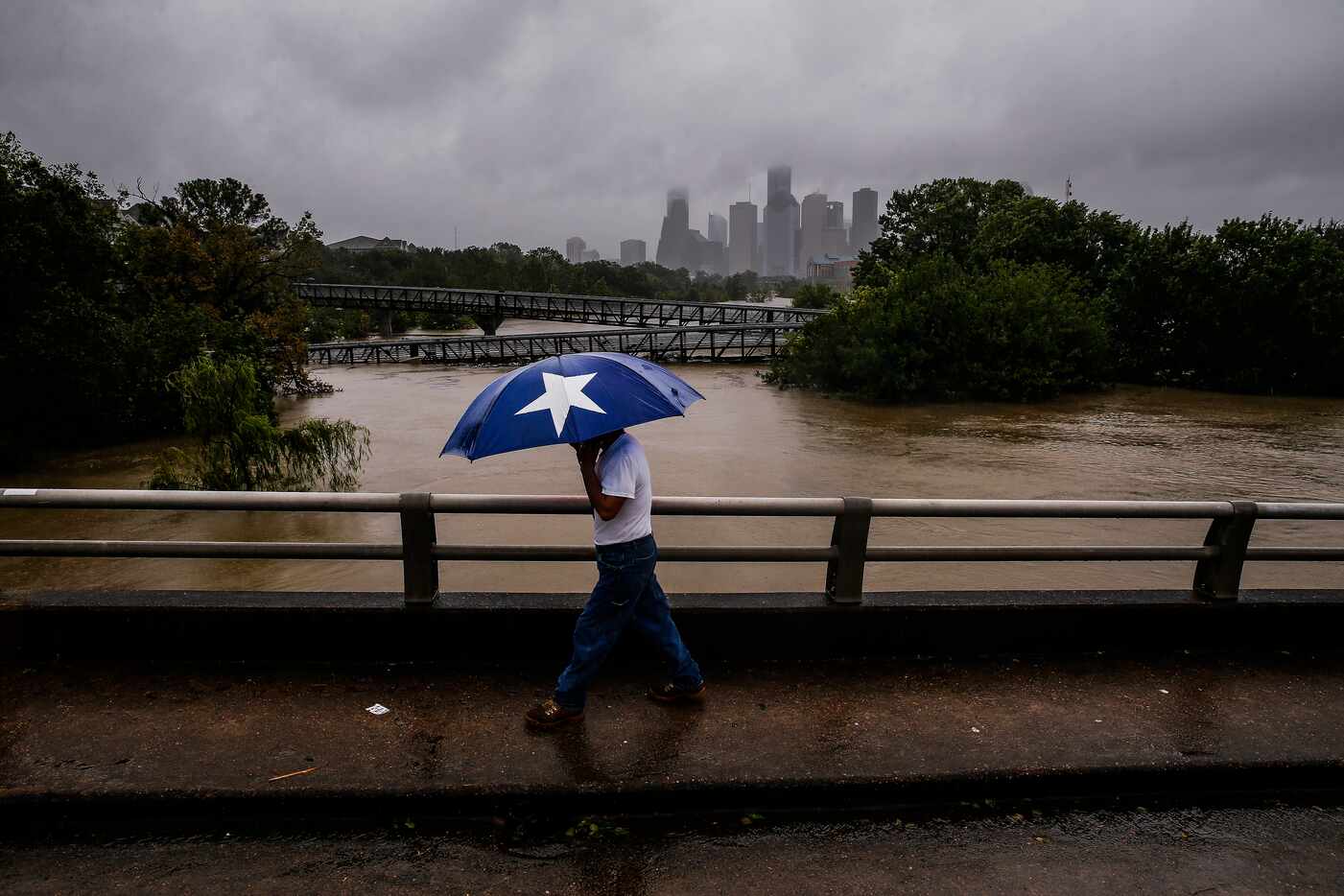 Armando Bustamante walks along the street over Buffalo Bayou as flood waters from Tropical...
