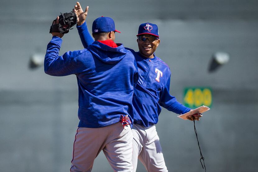 Texas Rangers third base coach Tony Beasley (right) high fives shortstop Elvis Andrus after...