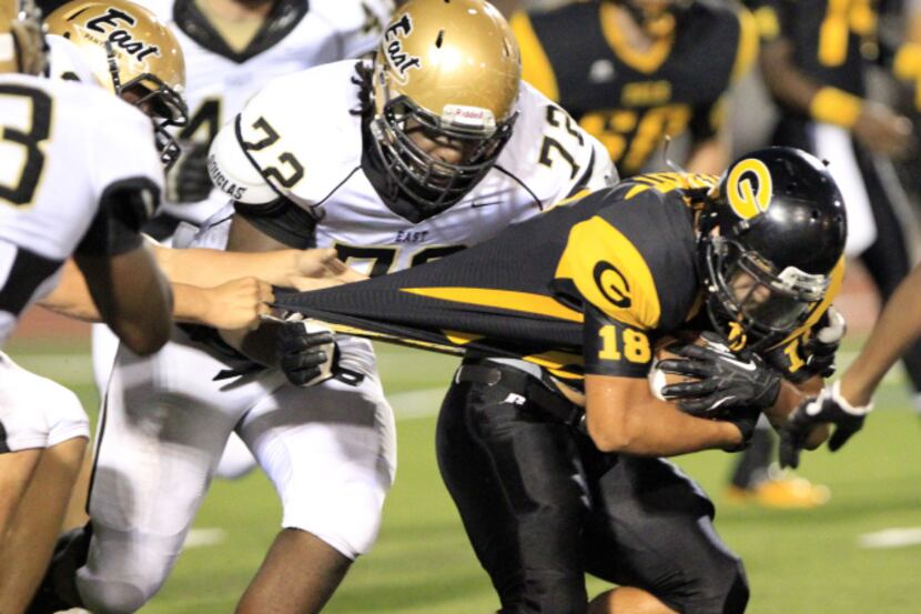 Garland High's Gabriel Theriot (18) is held up by several Plano East defenders, including...