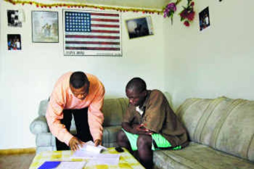 Pastor Bright Osigwe (left) completes paperwork to supply 10 days of food for an immigrant...