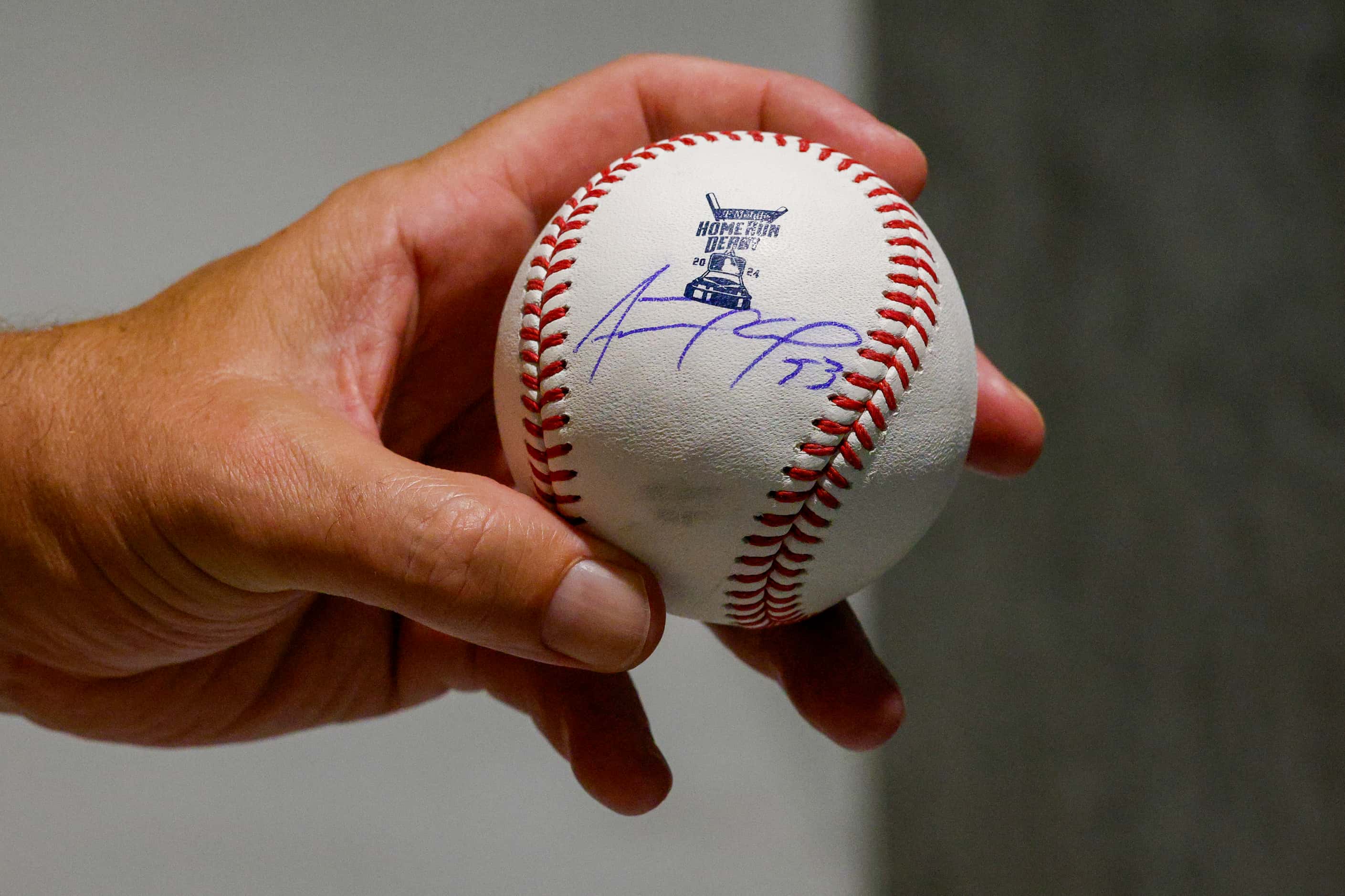 Joe Deane of Alvin, Texas holds an autographed baseball by Texas Rangers hitter Adolis...