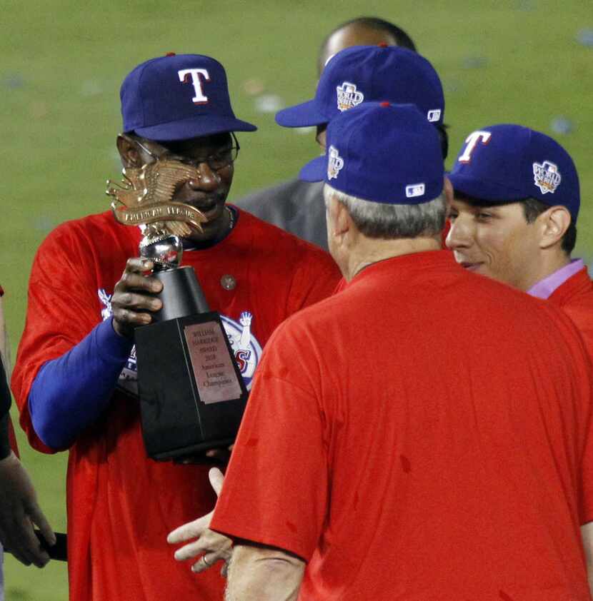 FILE - Texas Rangers manager Ron Washington, left, hands the ALCS trophy back to co-owner...