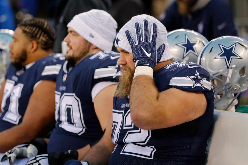 Dallas Cowboys center Travis Frederick (72) adjusts his cap on the sideline as he sits next...