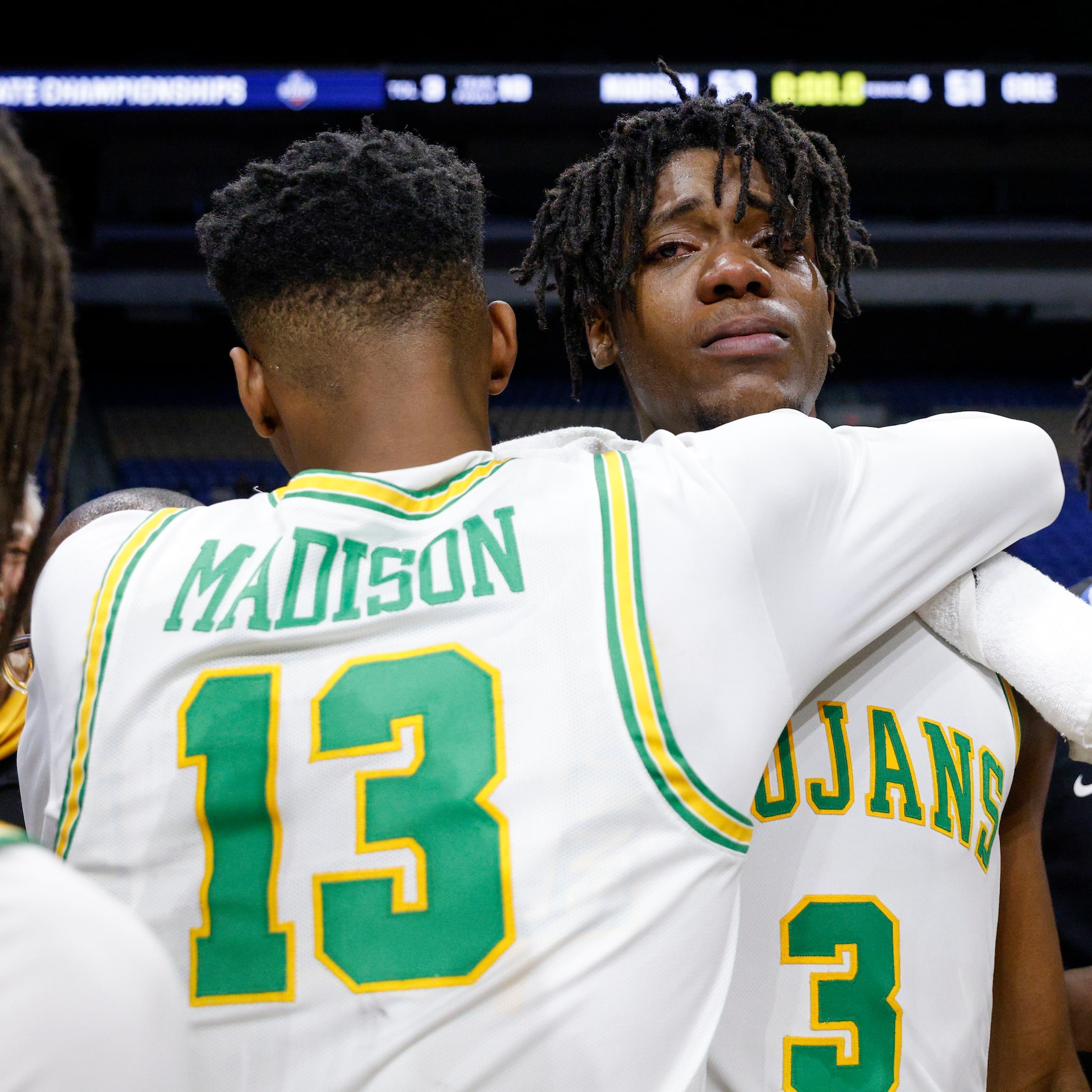 Madison forward Rodney Geter (13) hugs Madison forward Leonard Miles IV (3) as he is...