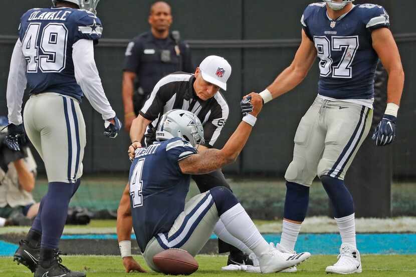 Cowboys quarterback Dak Prescott (4) is helped to his feet by Geoff Swaim (87) after getting...