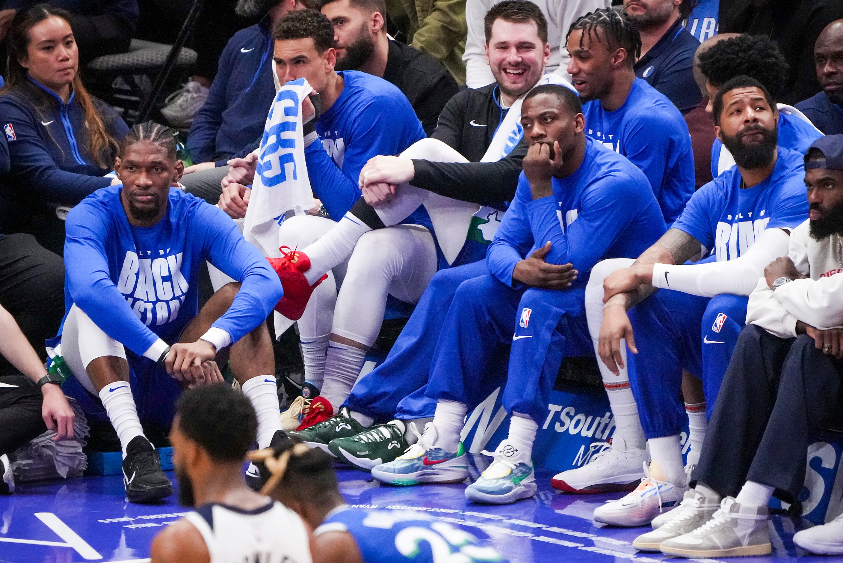 Dallas Mavericks guard Luka Doncic (center) smiles as he watches from the bench during the...