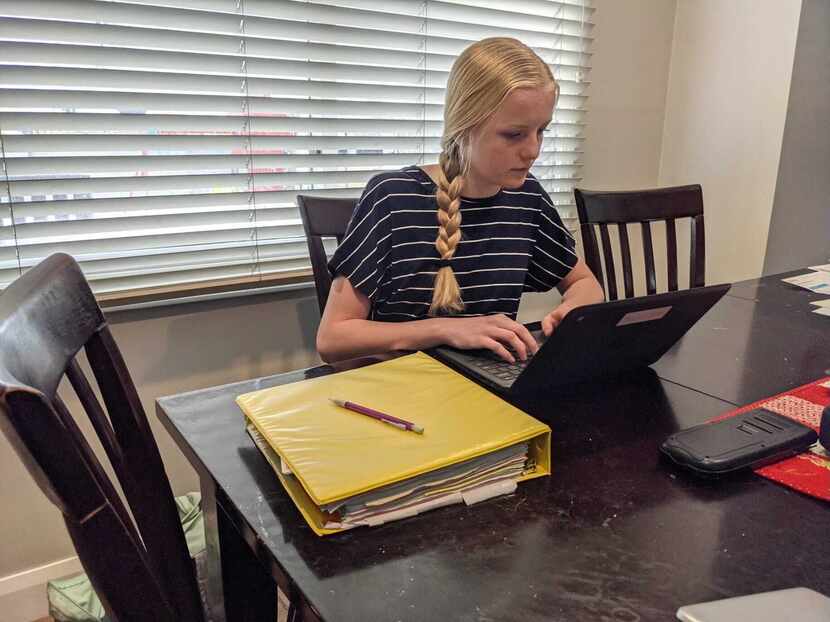 Ninth grader Kate Bowen completes homework in her family's dining room with the help of...