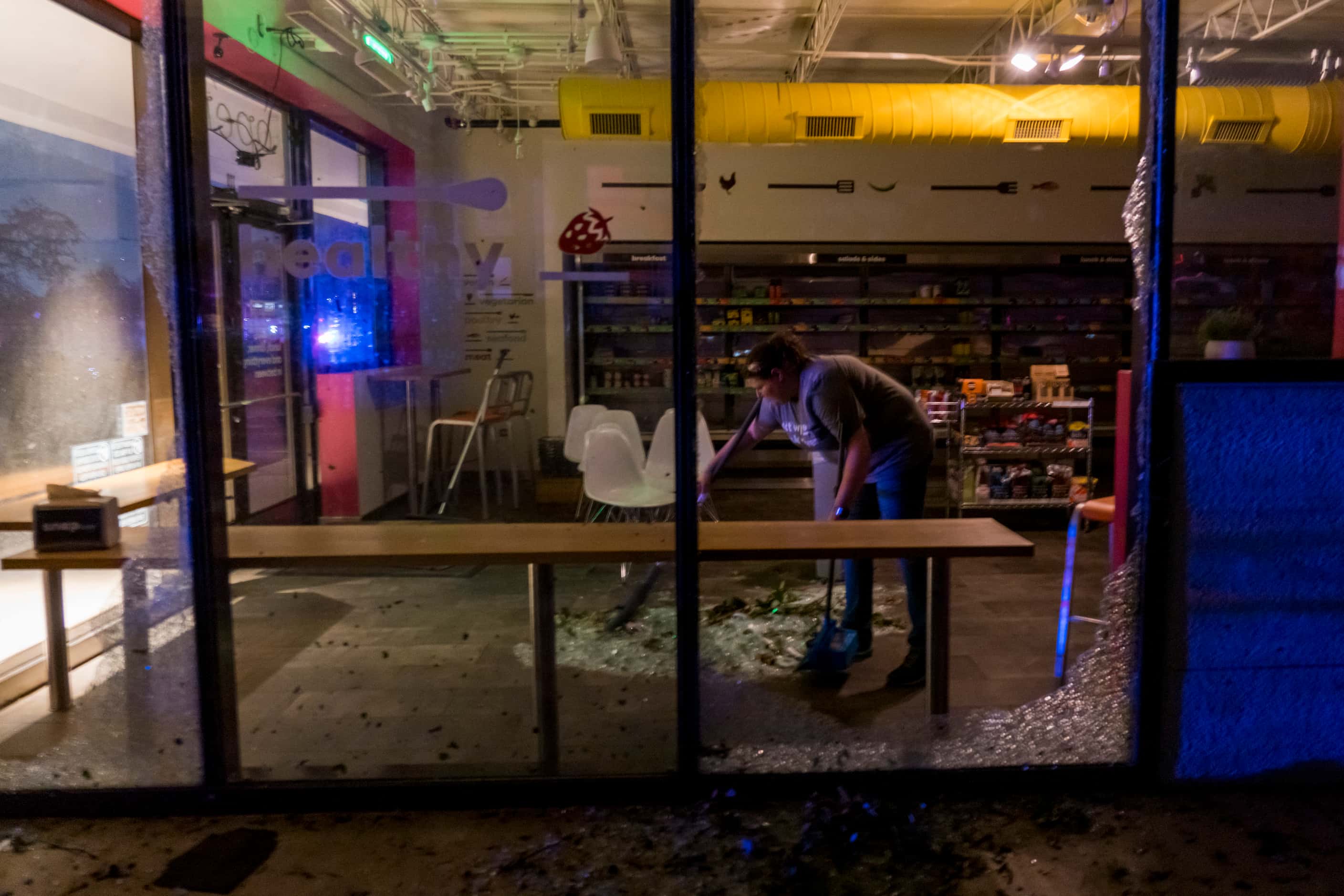 Anna Waugh  cleans up shattered glass from a business after tornado damage near the...