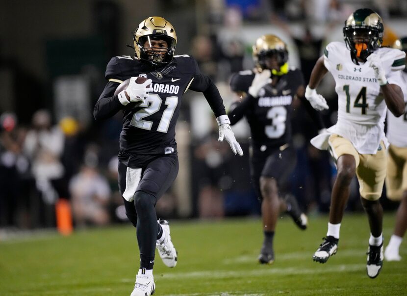 Colorado safety Shilo Sanders, left, runs back an interception for a touchdown as Colorado...