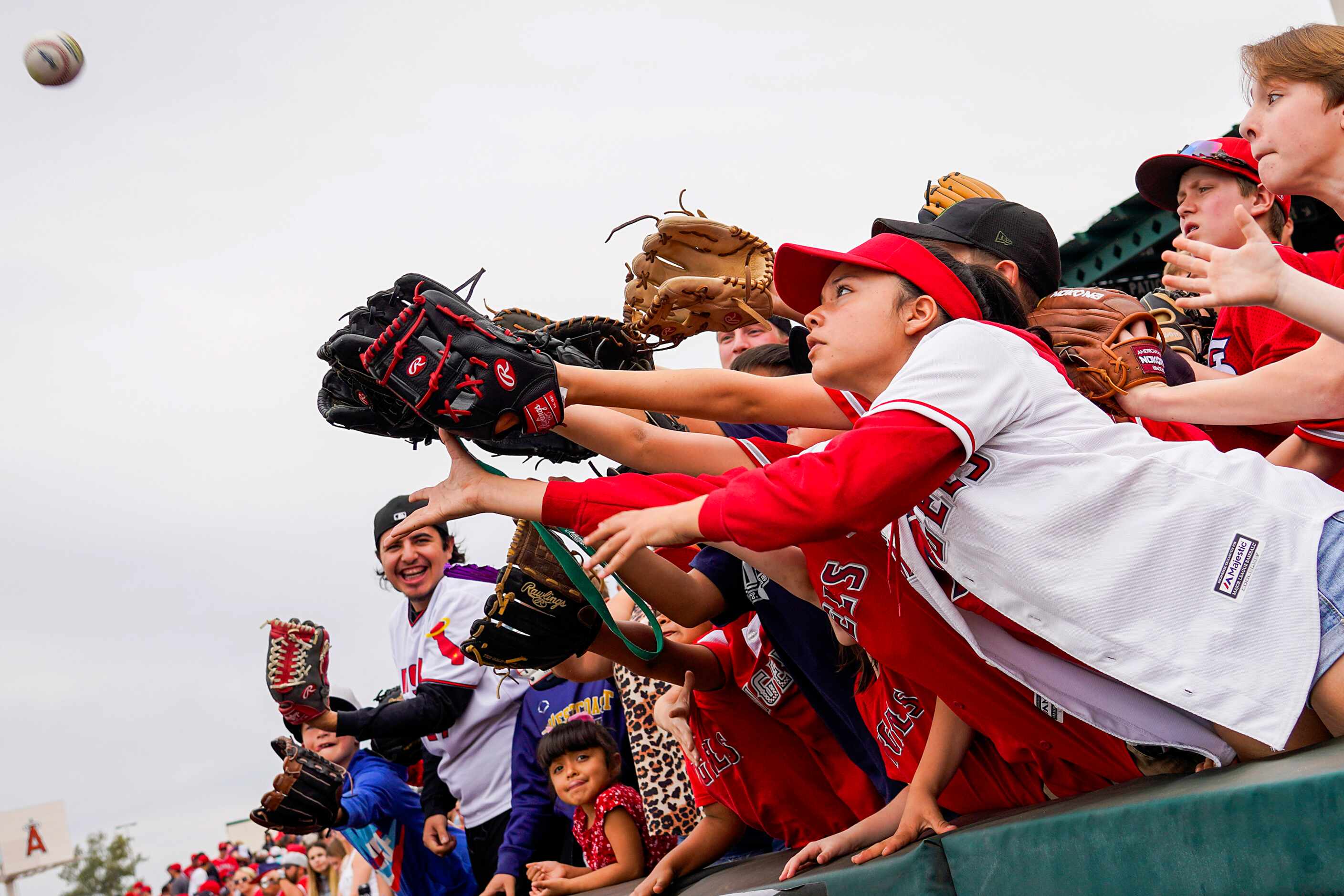 Young fans reach for a ball tossed into the stands by Los Angeles Angels first baseman...