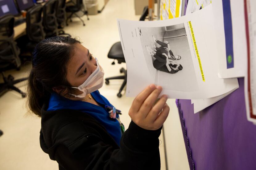 Registered nurse Kristen Maschino looks at an article about burn out among nurses pinned on...