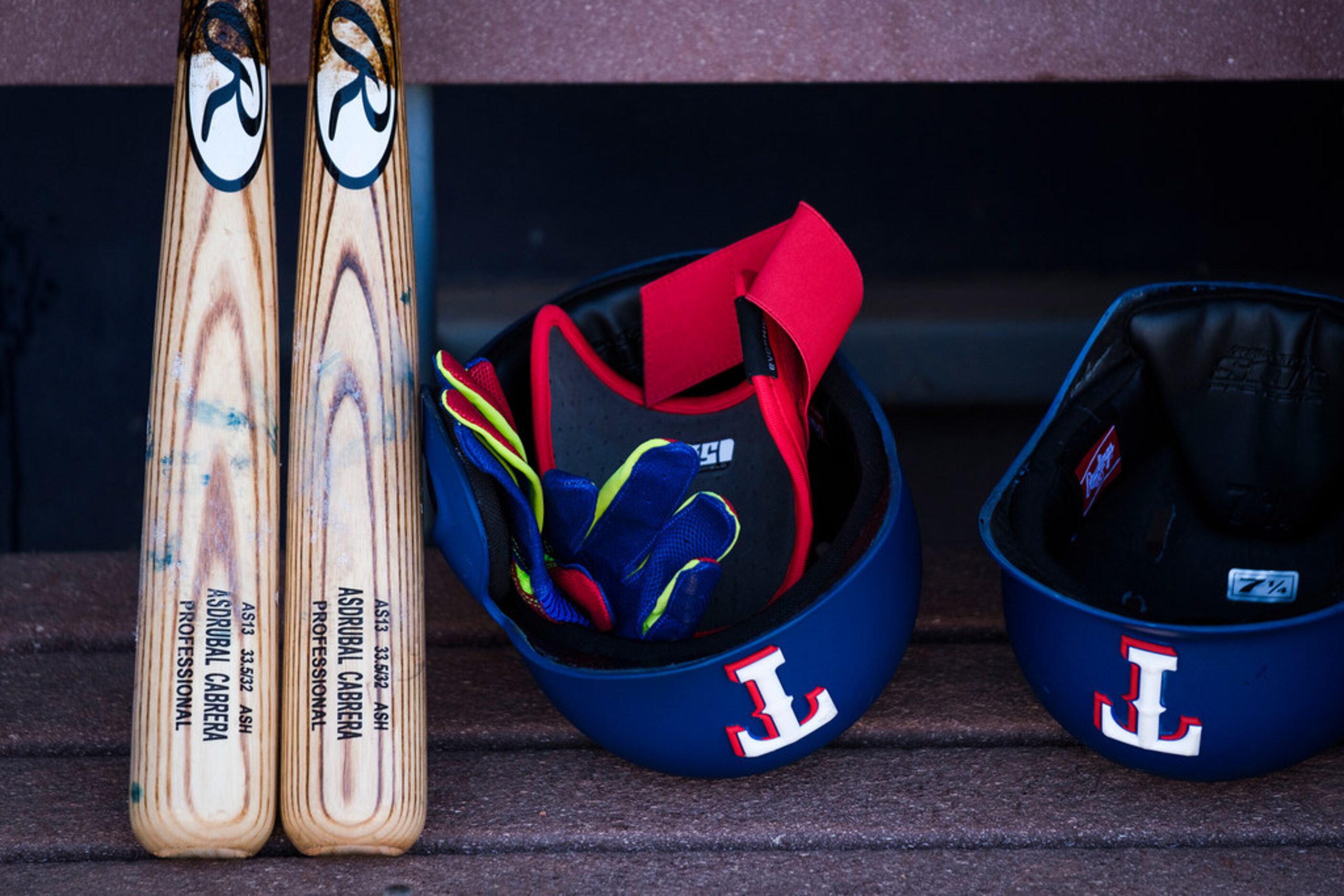 Texas Rangers third baseman Asdråbal Cabrera's bats and helmets sit in the dugout before a...