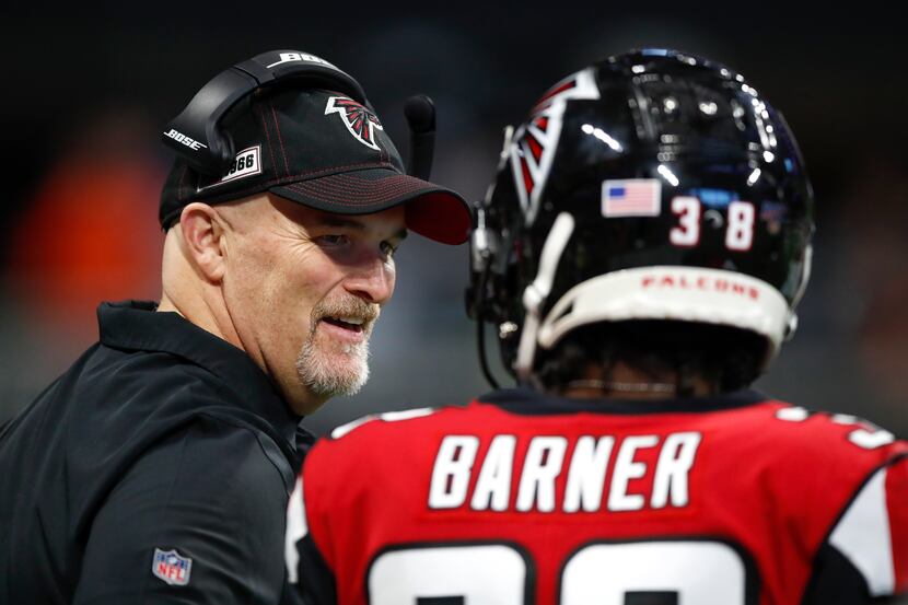 Head coach Dan Quinn of the Atlanta Falcons speaks with Kenjon Barner #38 in the second half...