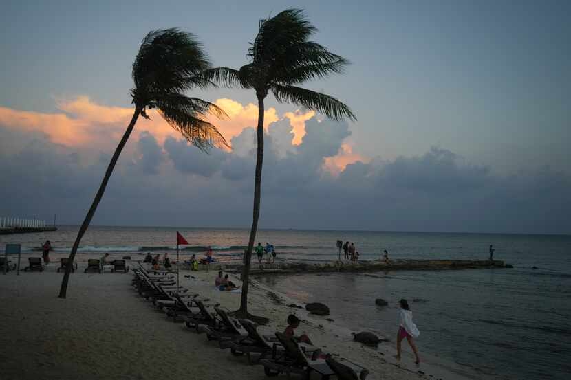 Gente en la playa mientras se pone el sol antes de la llegada del huracán Beryl en Playa del...