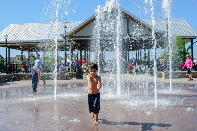 Blake Saunders, 4, runs through the fountains outside the pavilion at the Coppell Farmers...