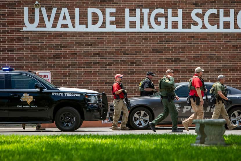Law enforcement personnel walk outside Uvalde High School after shooting a was reported...