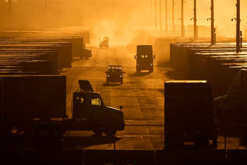 Workers drive among shipping containers and trailers at a BNSF intermodal terminal, Jan. 3,...