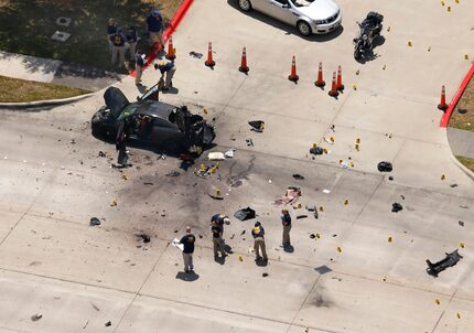 Investigators work near the car of the assailants who shot a security guard at the Curtis...