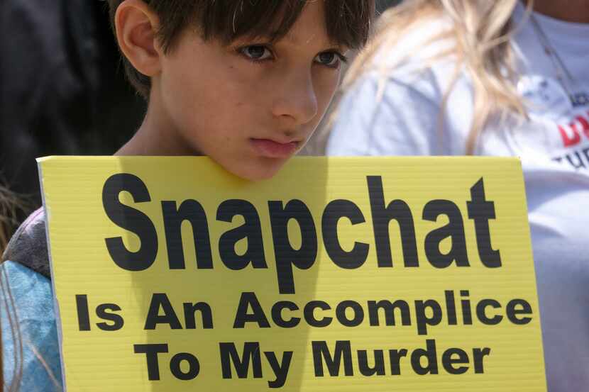 A young person holds a sign as people opposed to the sale of illegal drugs on Snapchat...