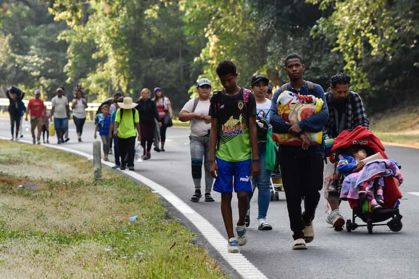 Migrants walk on the side of the highway through Villa Comaltitlan, Chiapas state, southern...