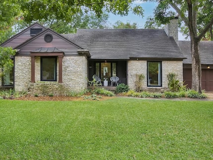 Exterior of stone cottage with green front yard and mature trees