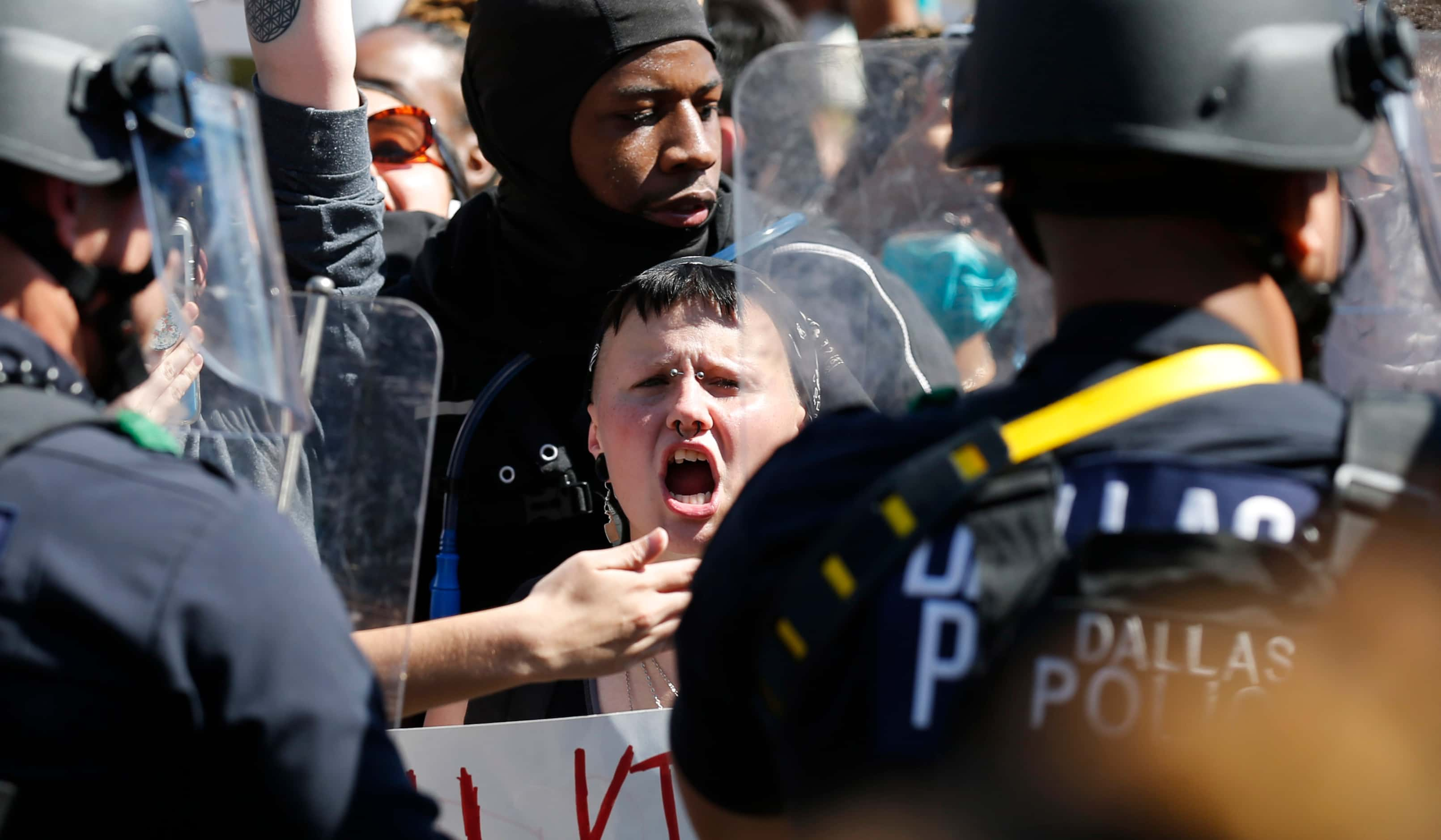 Protesters yell towards Dallas police as they protest against police brutality in downtown...