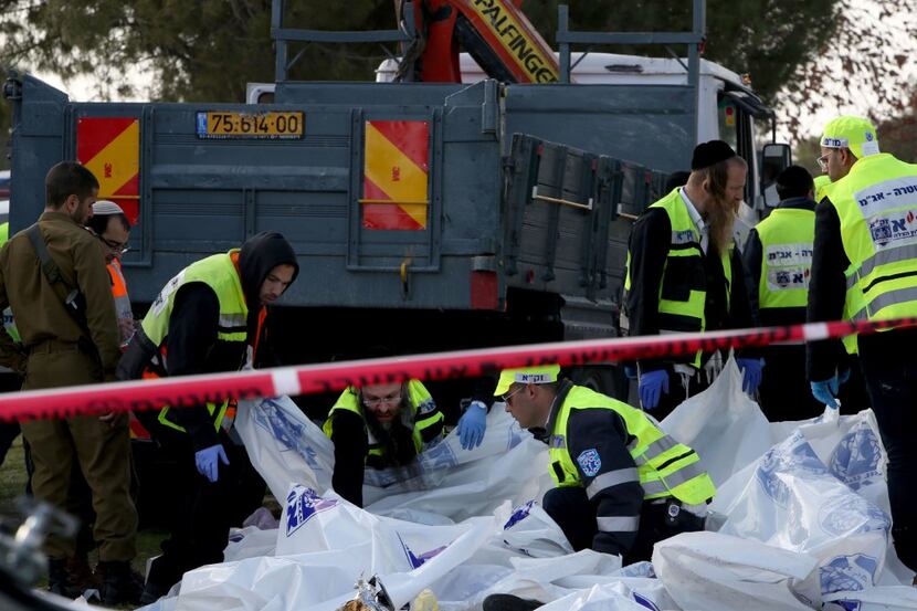 Israeli Zaka volunteers examine a body of one of the four Israeli soldiers killed when a...