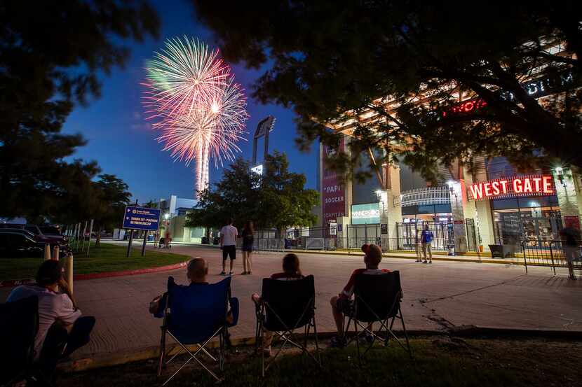 Fans relax in the parking lot and watch fireworks explode over Toyota Stadium after a 3-2...