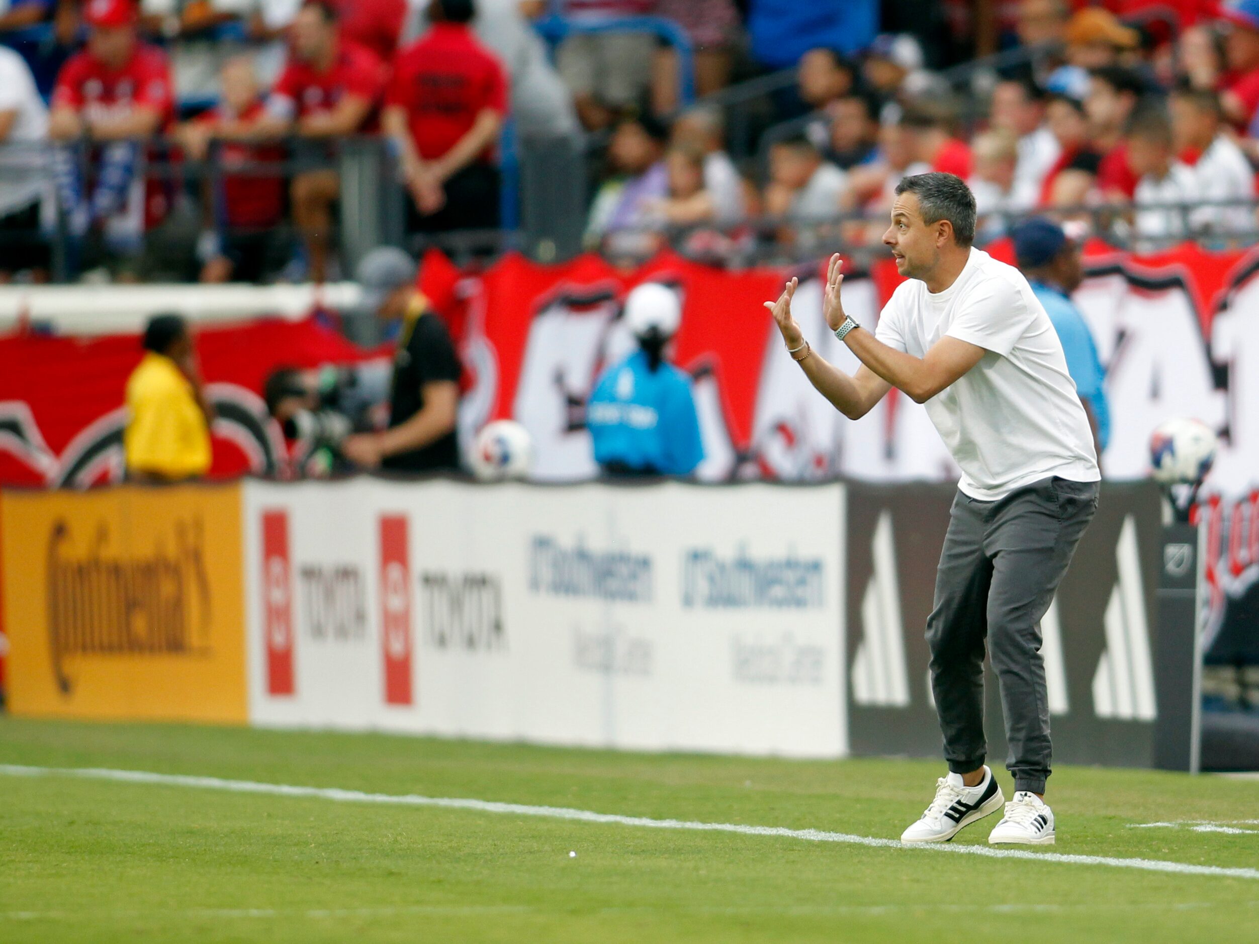 FC Dallas head coach Nico Esteves gestures to players from the team bench area during first...