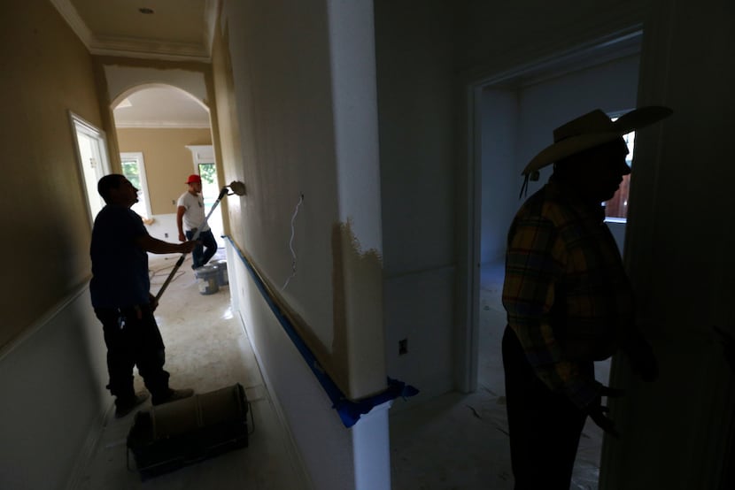 Santos Coria (right) gave a tour of one of his houses in West Dallas as workers painted the...