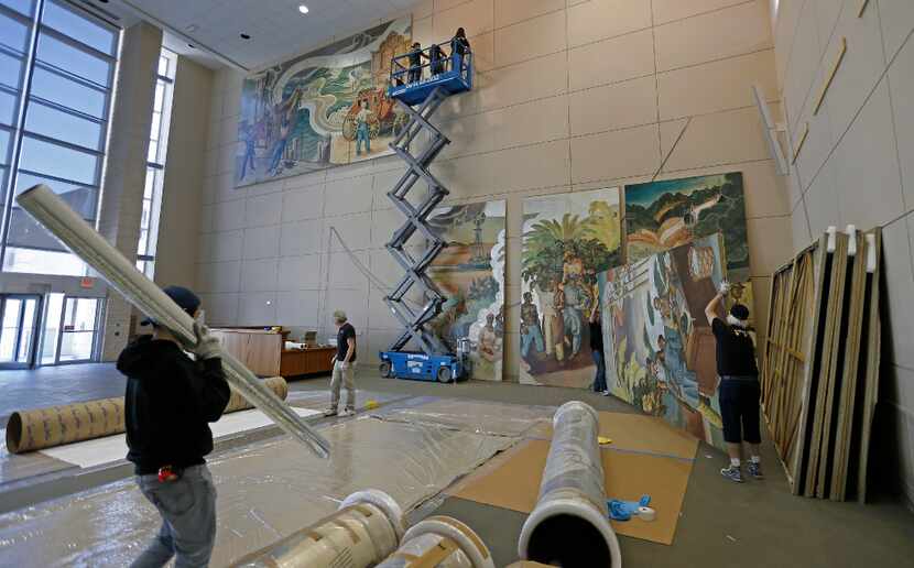 Workers from Unified Fine Arts remove artwork from the wall of the TXCN building on The...