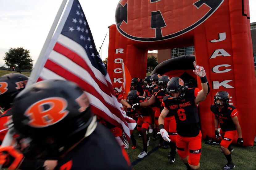 The Rockwall Yellowjackets enter the field before the start of a high school football game...