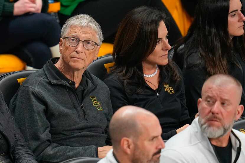 Bill Gates, left, sits with his girlfriend, Paula Hurd, during the first half of an NCAA...