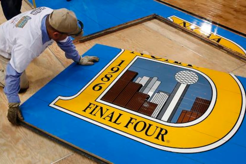 
Crews install the piece of floor honoring the 1986 Final Four in Dallas, in preparation for...
