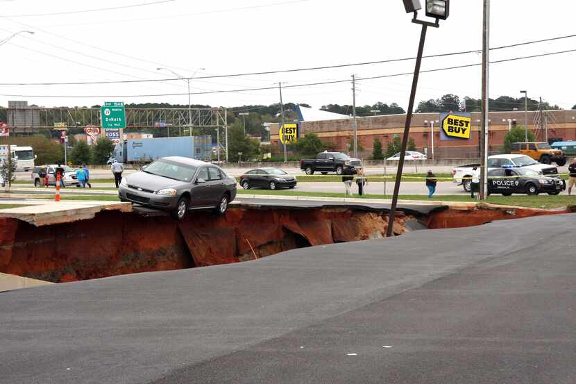 A car teetered on the edge of a cave-in of a parking lot in Meridian, Miss., on Sunday....